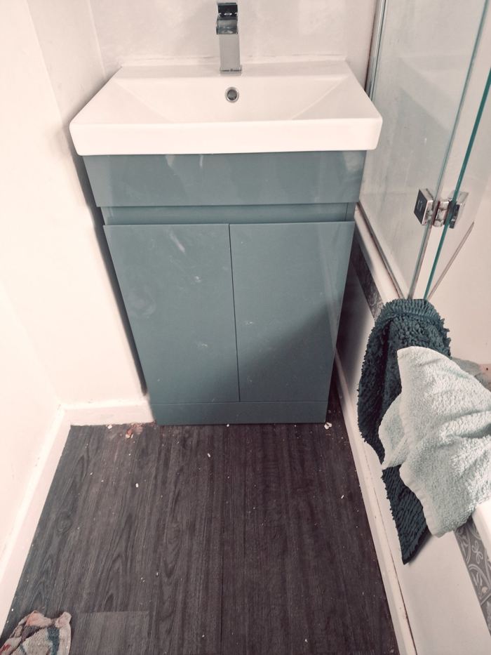 Wall-hung basin on a green vanity unit with tap fitted